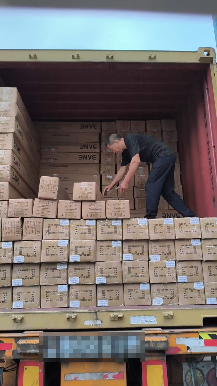 Worker stacking labeled cartons inside an open shipping container
