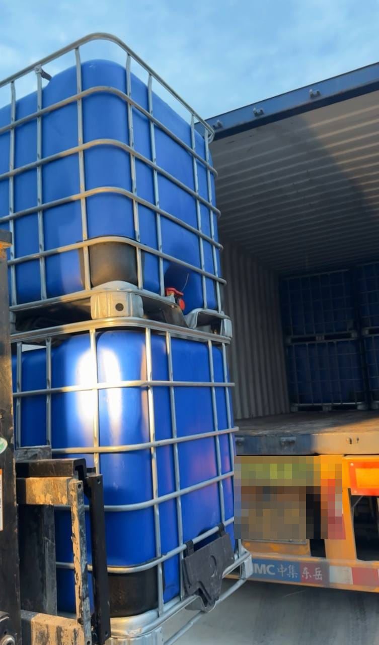 Forklift lifting a stacked blue IBC tank next to a container